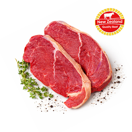 Two raw steaks with herbs and spices on a white background, featuring the New Zealand Quality Beef logo.